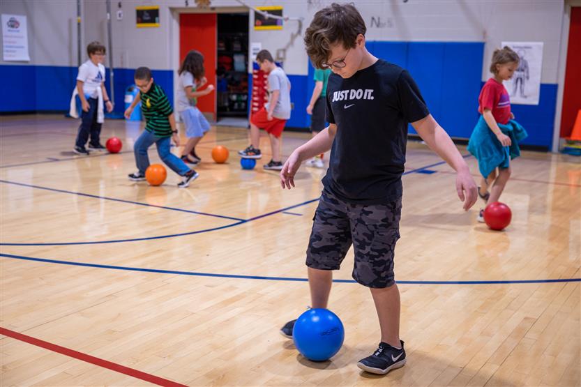 A boy dribbles a soccer ball in a gym